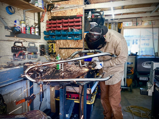 Firefighter-owned metal fabrication shop grinding a custom tube-bent stunt cage for a dirt bike. Precision-built, made in Idaho by Weiser River Fab.