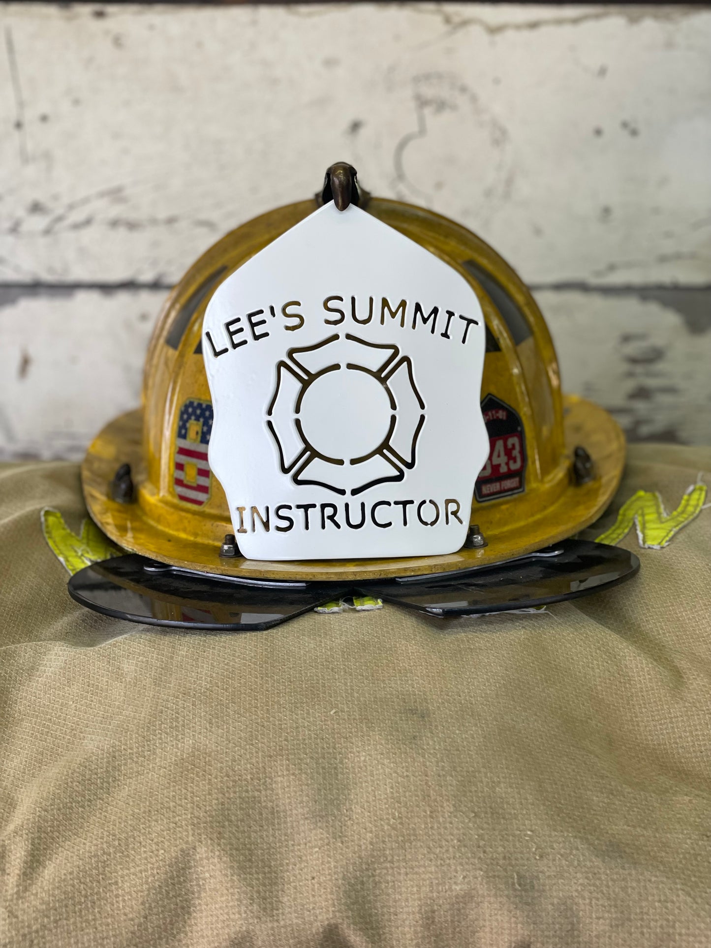 "Custom white powder coated metal firefighter helmet shield mounted on a Cairns traditional helmet, personalized with department name, unit number, and firefighter name, offering a sleek, durable design for professional firefighting gear."