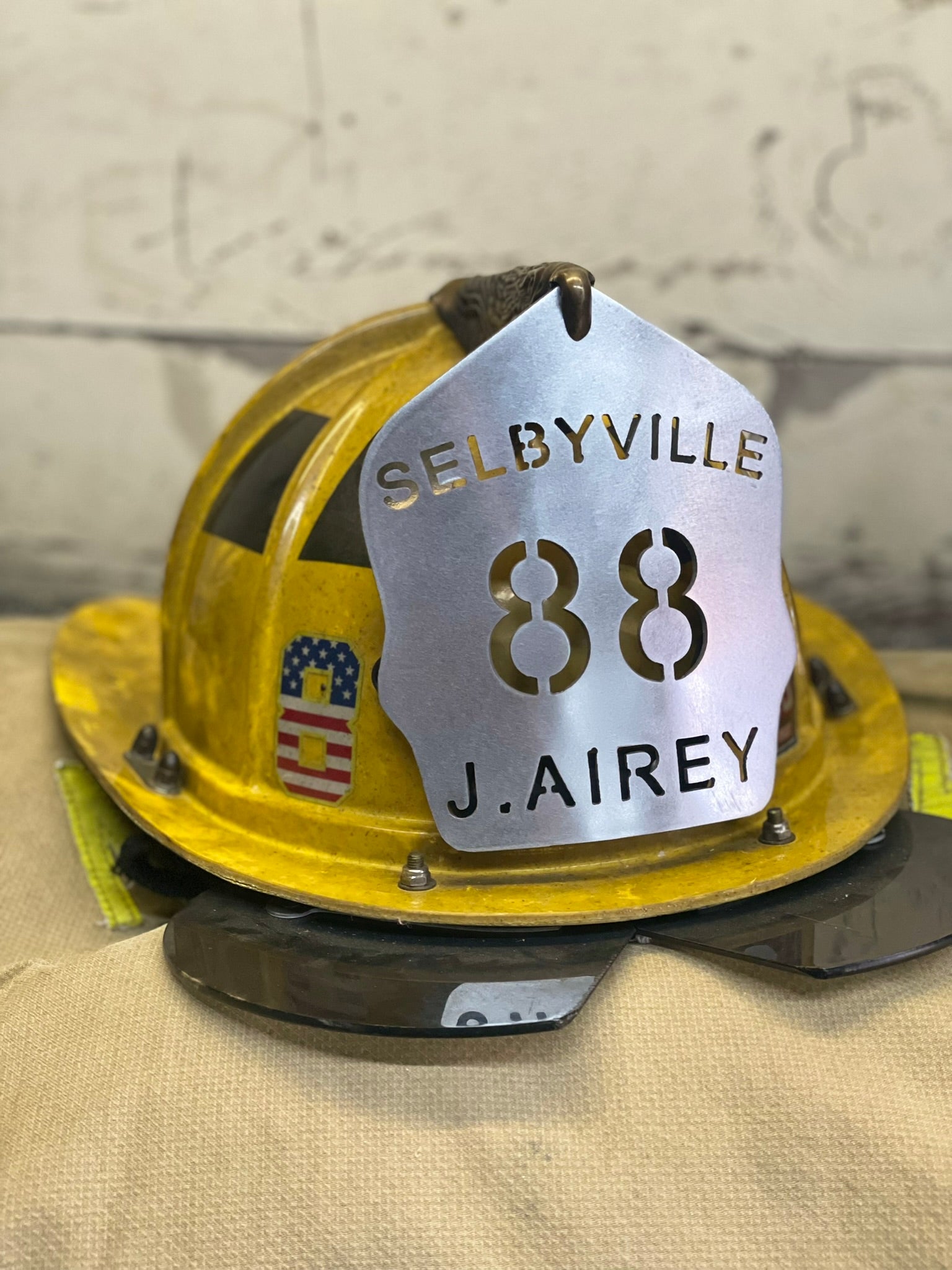 "Custom traditional raw metal firefighter helmet shield mounted on a Paul Conway traditional helmet, personalized with department name, unit number, and firefighter name, perfect for professional firefighting gear."