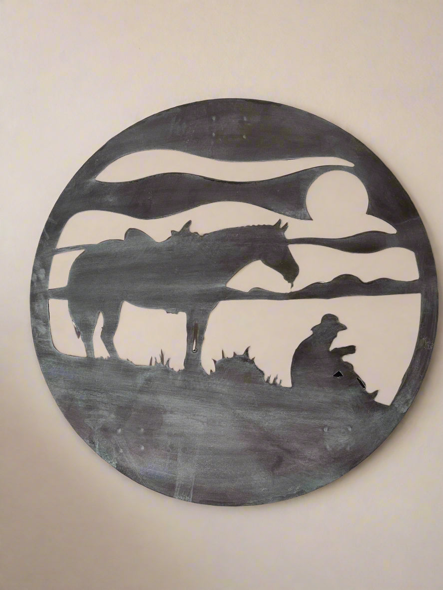 "Round metal sign featuring a cowboy drinking coffee with a sunrise backdrop, rustic western design with vintage style, ideal for country home decor or ranch-themed spaces."