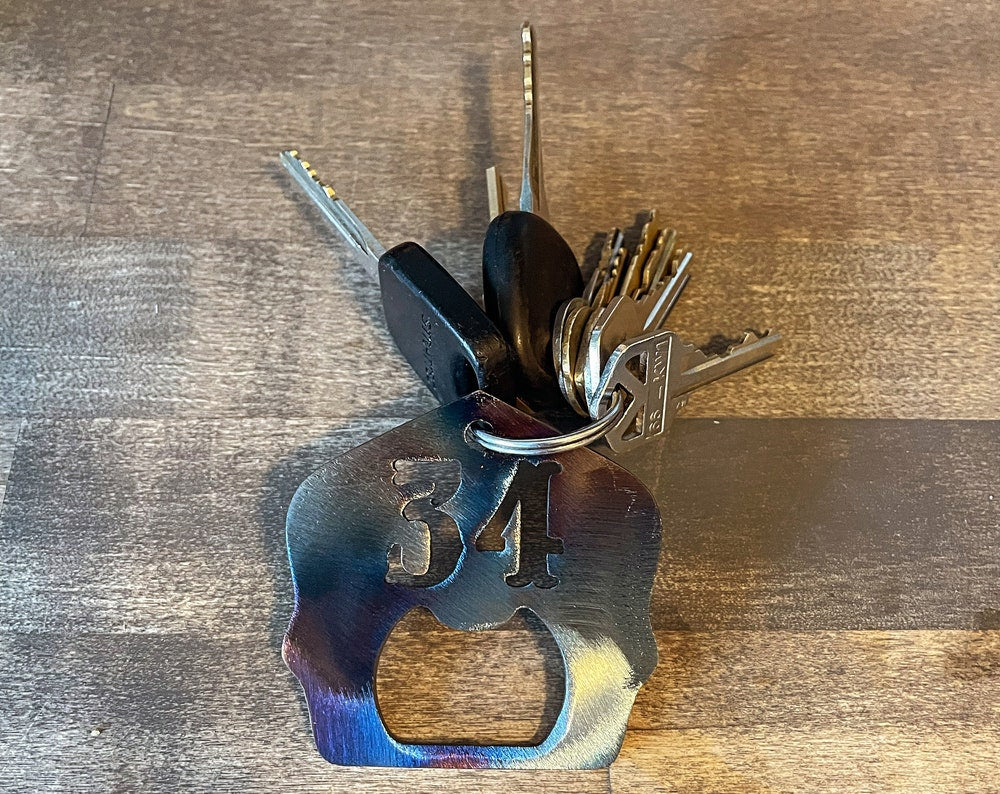 "Torch patina firefighter helmet shield keychain with built-in bottle opener and personalized unit number, custom firefighter accessory with rugged, unique finish for keys or gear."